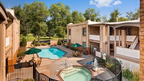 A residential building with a swimming pool, outdoor seating, and a view of a golf course. - Best Western Plus Plaza Hotel (Thermopolis)