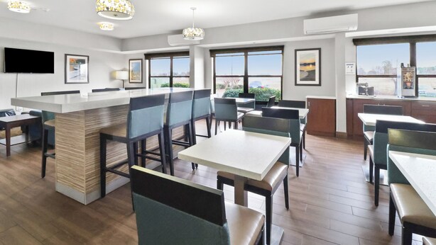 A modern dining area with a central bar, multiple seating options, and large windows offering views.