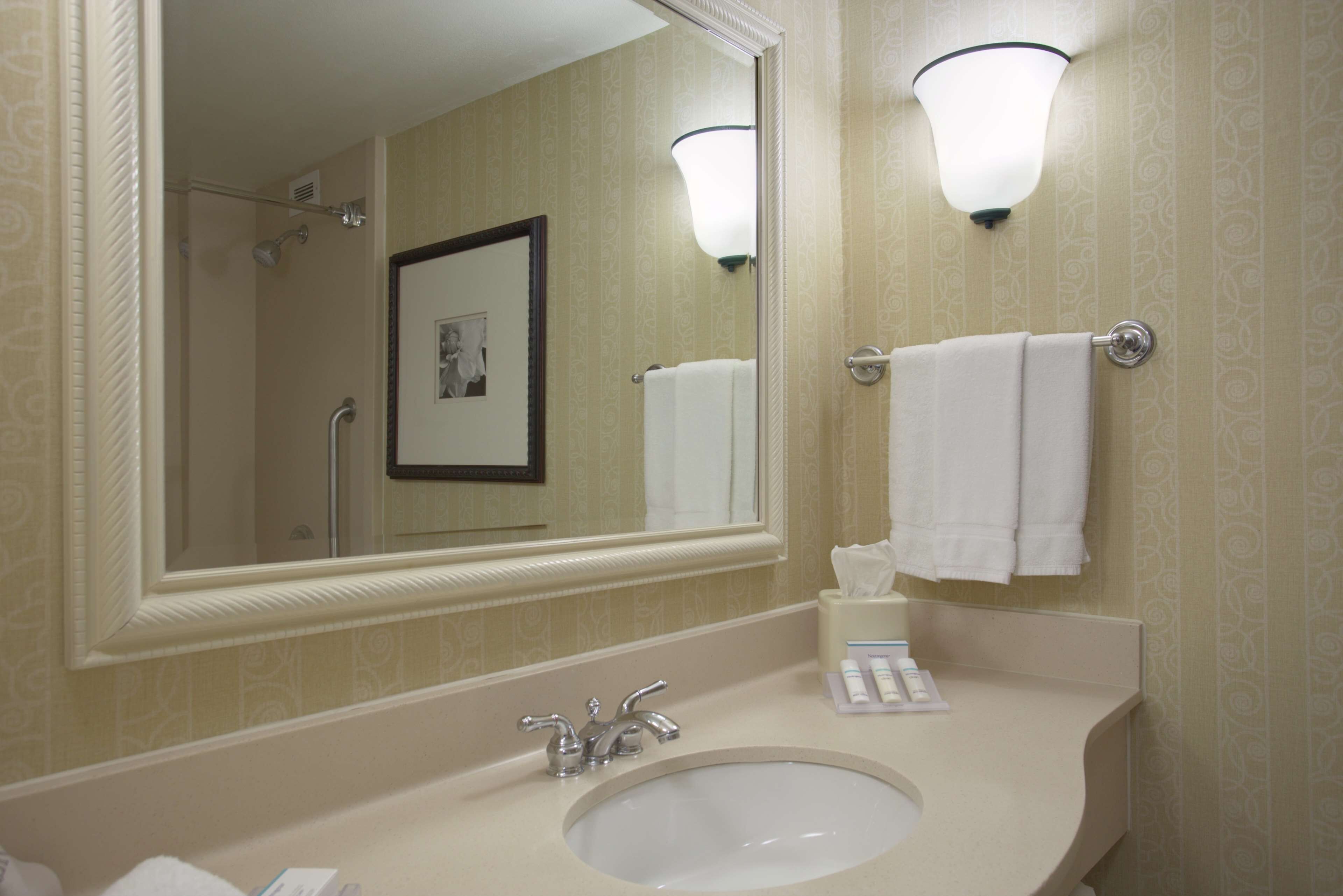 A bathroom with a sink, mirror, and towel rack.