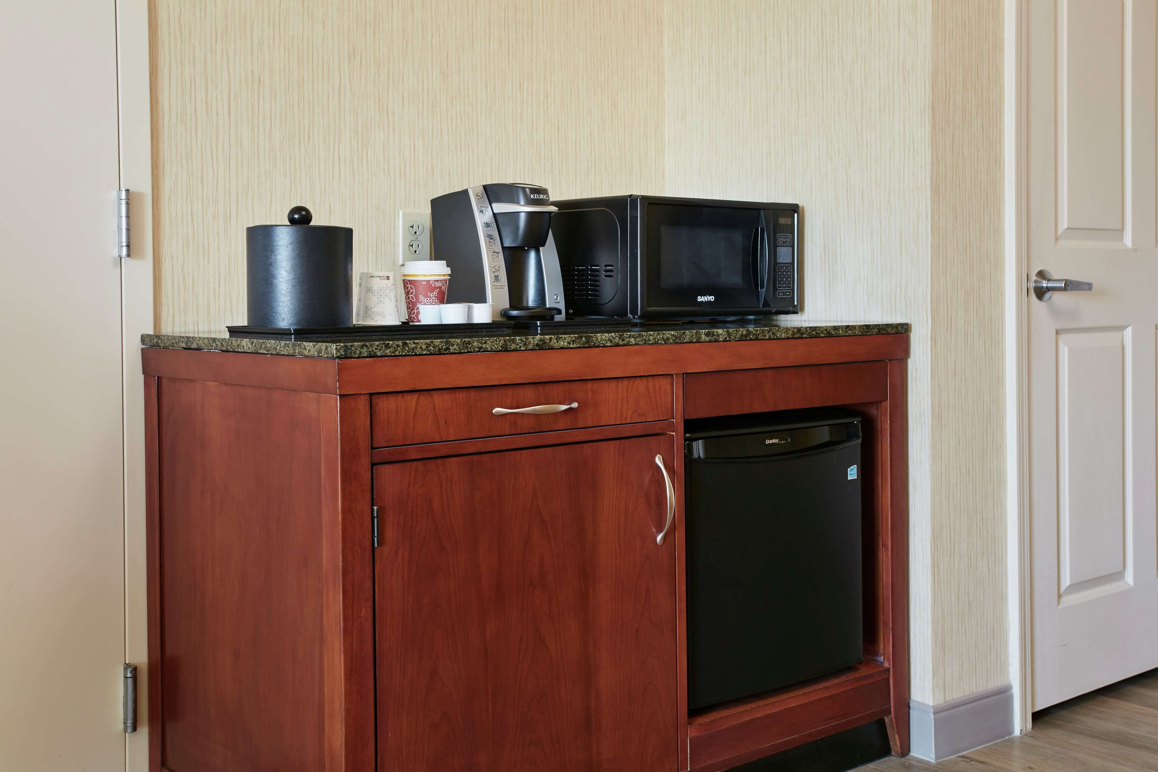 A compact kitchen with a coffee maker, microwave, and a small refrigerator.