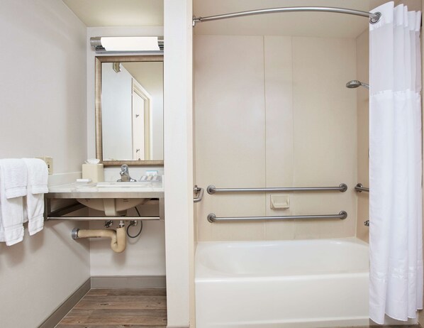 A bathroom with a bathtub, a sink, a mirror, and a shower curtain.