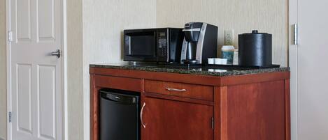 A kitchen with a microwave, coffee maker, and a black container on the countertop.