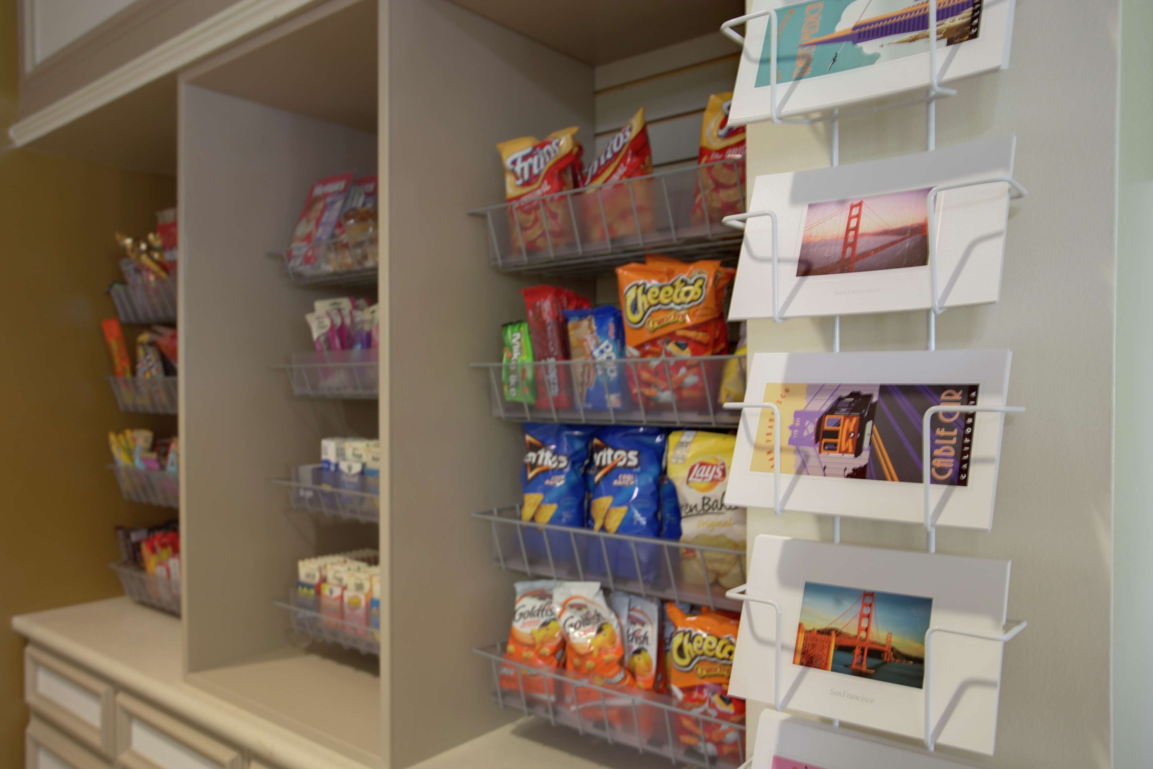 A pantry with shelves stocked with snacks and a display of postcards.