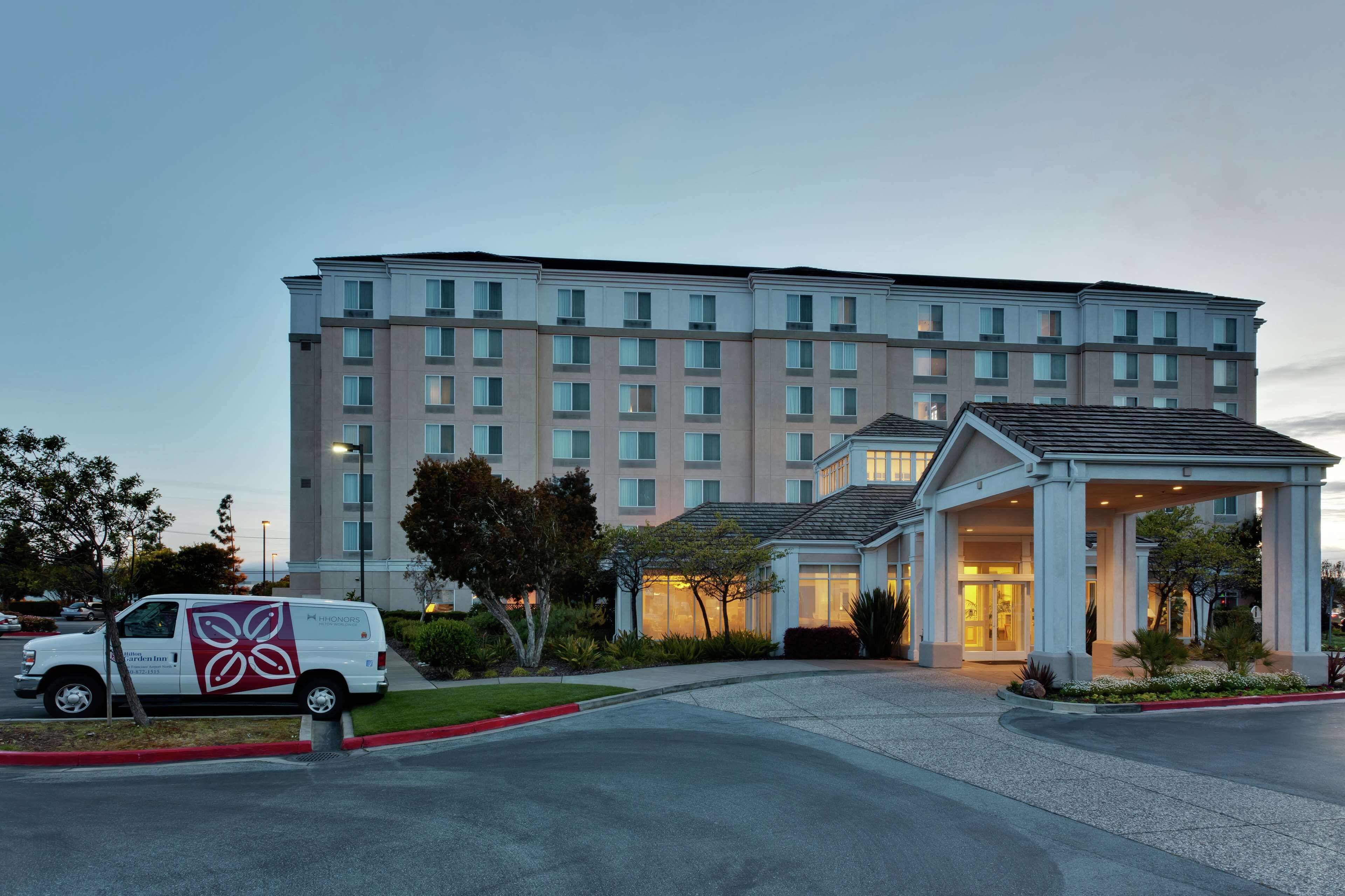 Un hotel de varios pisos con entrada central y zona de estacionamiento.