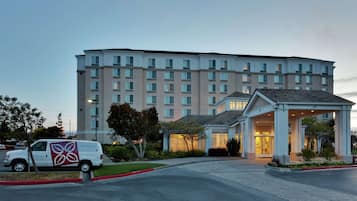 A multi-story hotel with a central entrance and a parking area.