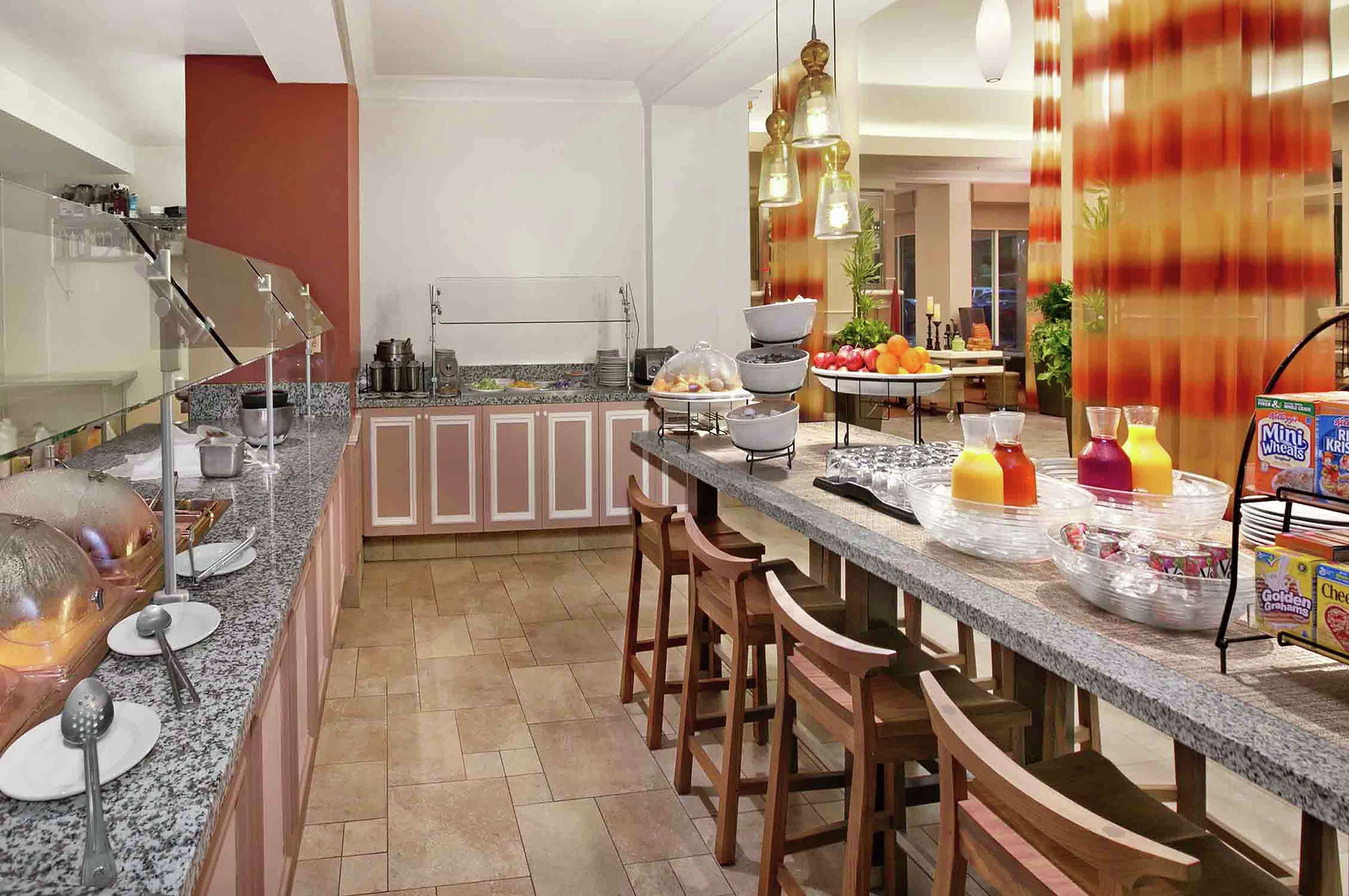 A modern kitchen with granite countertops, bar stools, and a breakfast bar.