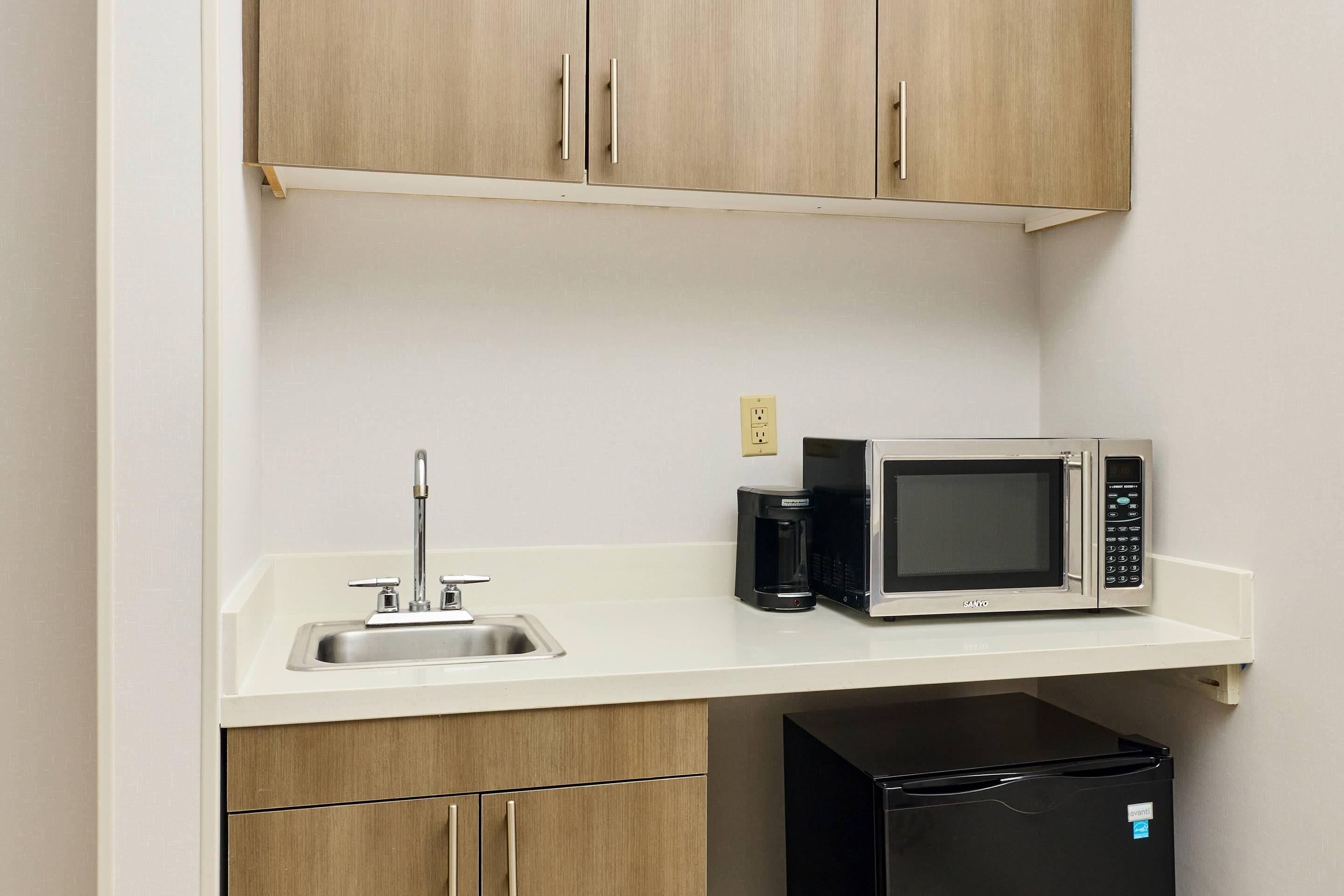 A kitchen with a microwave, coffee maker, and a refrigerator.