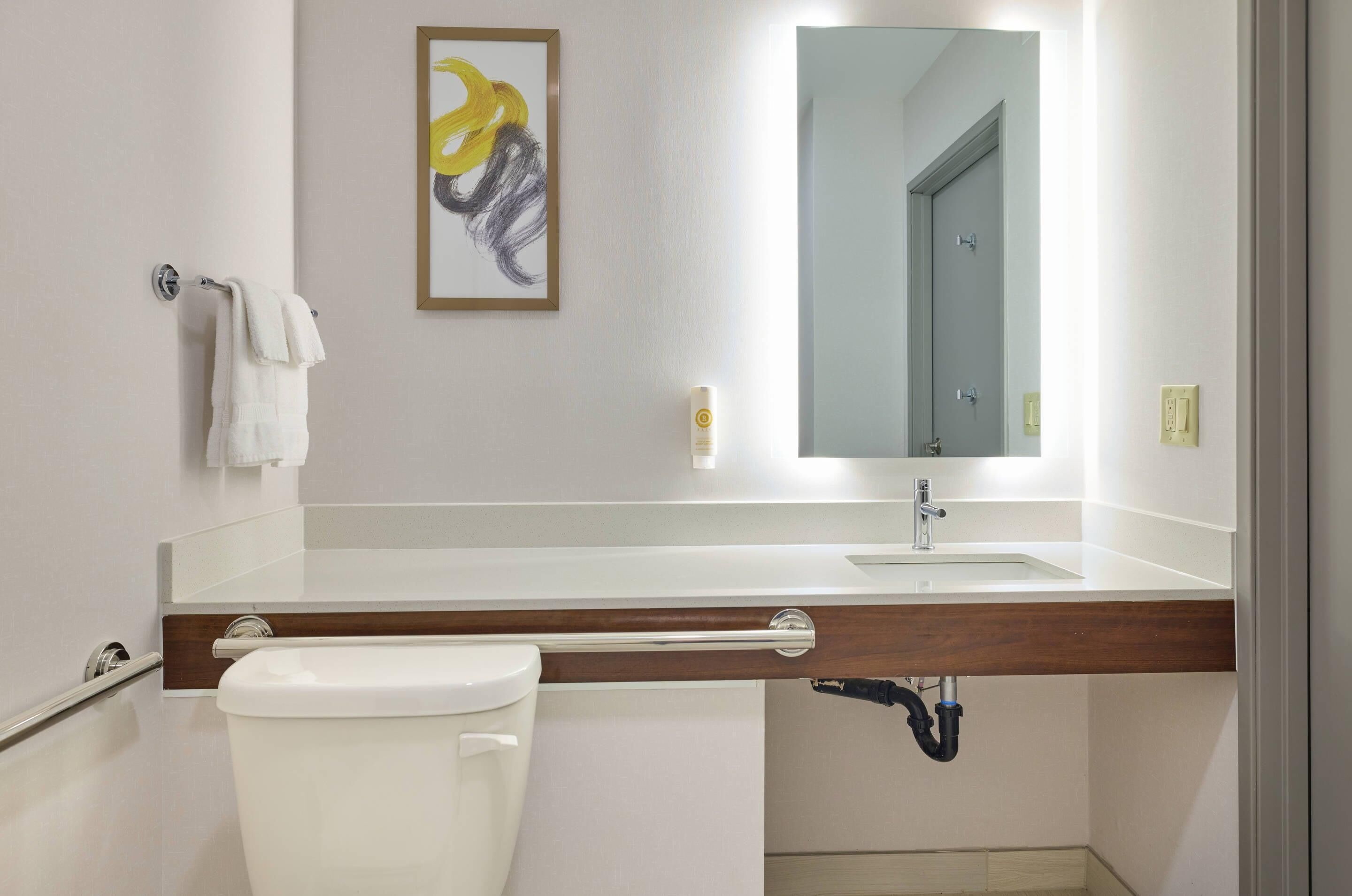 Ein modernes Badezimmer mit Toilette, Waschbecken und Spiegel.