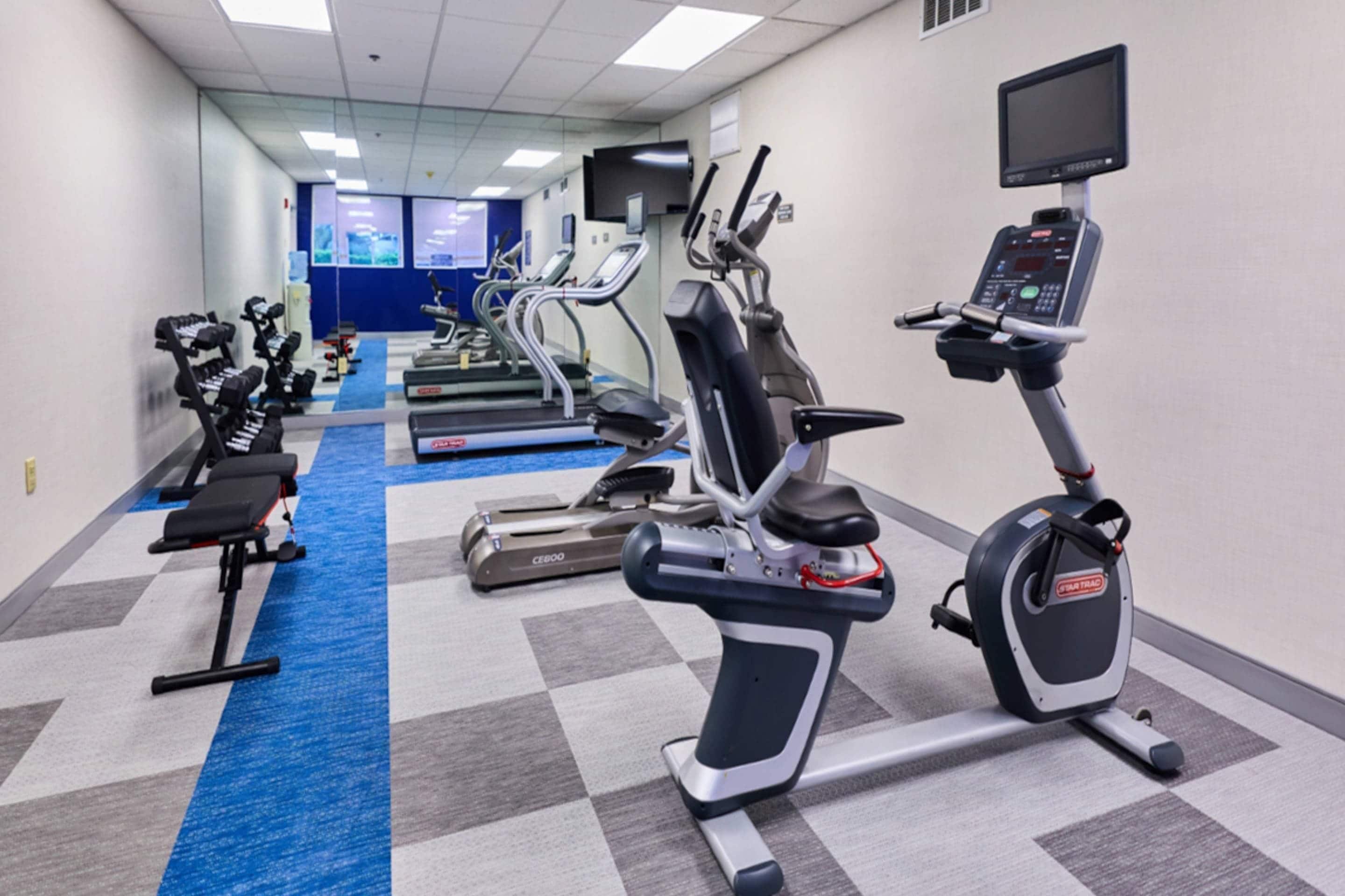 Un gimnasio con cintas de correr, bicicletas estáticas y máquinas de pesas.