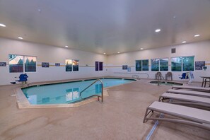 An indoor swimming pool with a clear view of the pool area, a lifeguard chair, and lounge chairs.