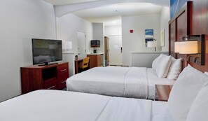 A hotel room with two beds, a TV, a desk, and a chair.
