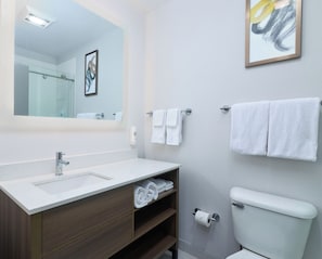 A modern bathroom with a white sink, wooden vanity, a toilet, and a shower. - Comfort Suites Springfield-Eugene (Springfield)