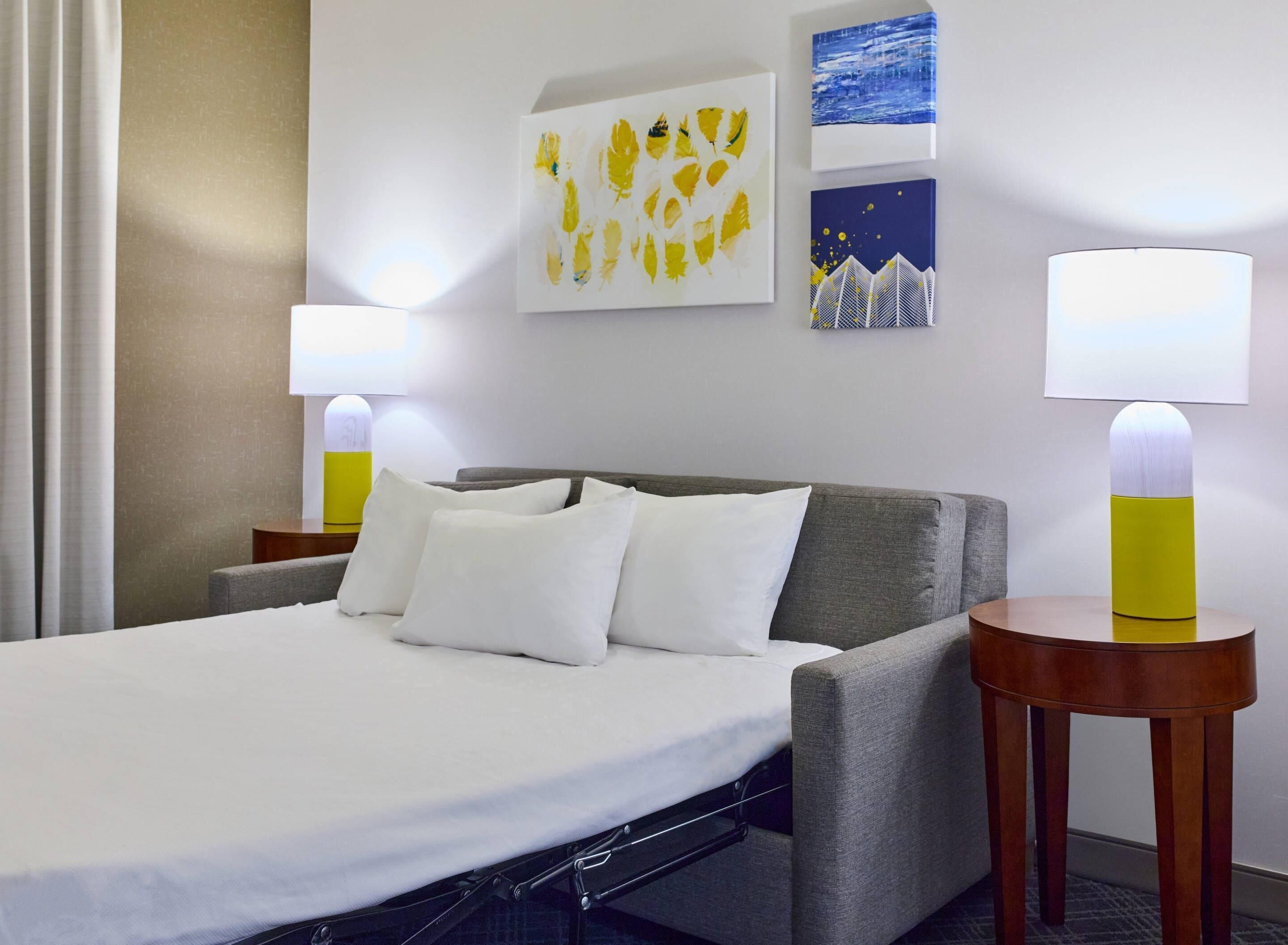 Una habitación de hotel con cama, dos mesitas de noche y decoración en la pared.