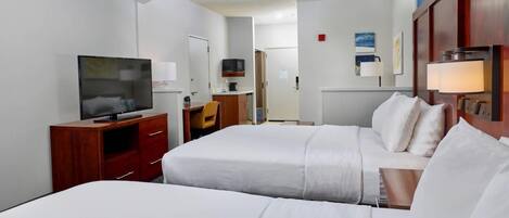 A hotel room with two beds, a TV, a desk, and a chair.