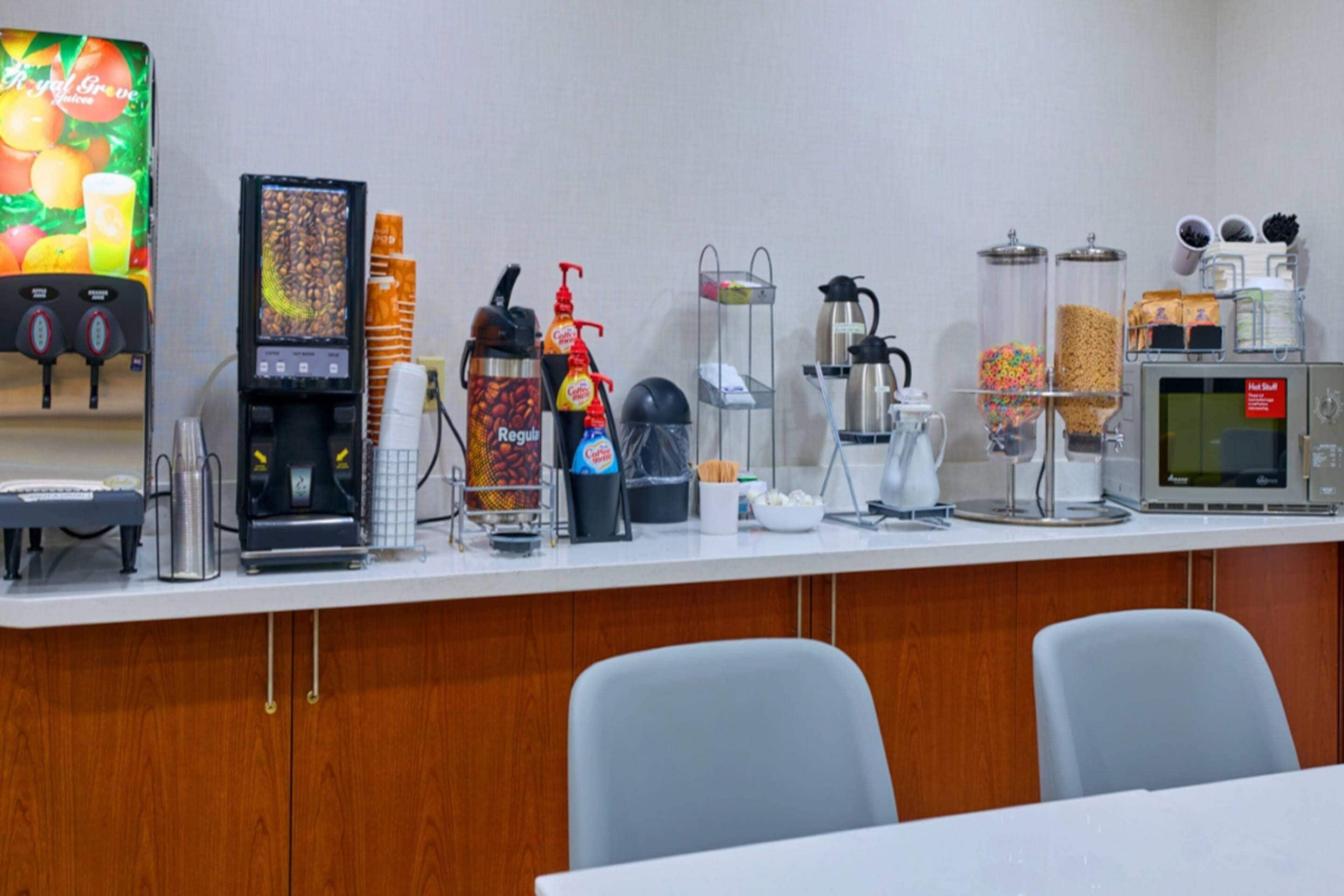 A breakfast bar with a coffee machine, a microwave, and various food containers.