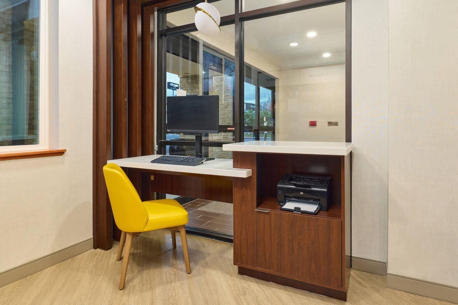 A small office area with a desk, a yellow chair, a computer, and a printer.