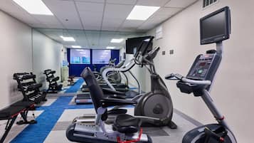 Un gimnasio con cintas de correr, elípticas y bancos de pesas.