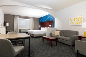 Une chambre d’hôtel avec un lit, un canapé, une table à manger et un téléviseur.
