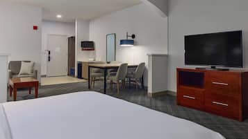 A hotel room with a bed, a desk with a chair, a television, and a wardrobe.