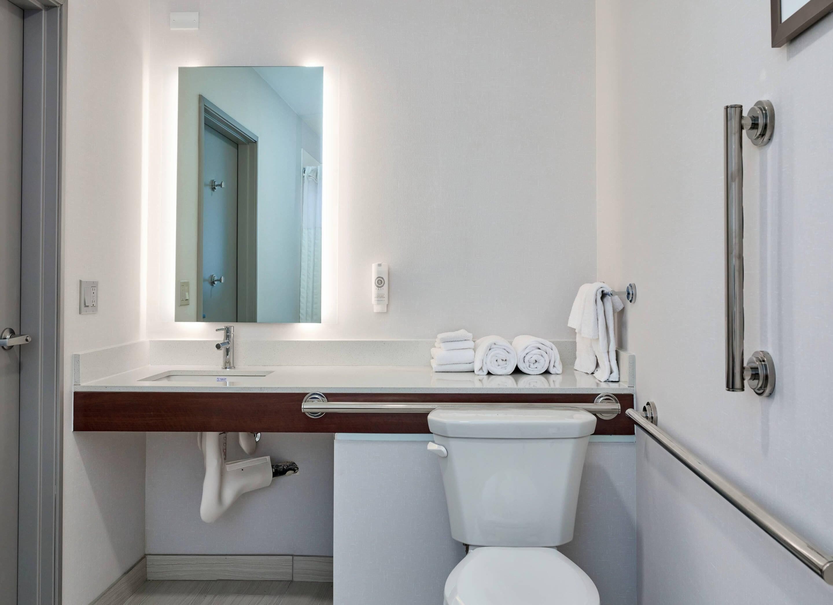 A modern bathroom with a white sink, a mirror, a toilet, and a shower area.