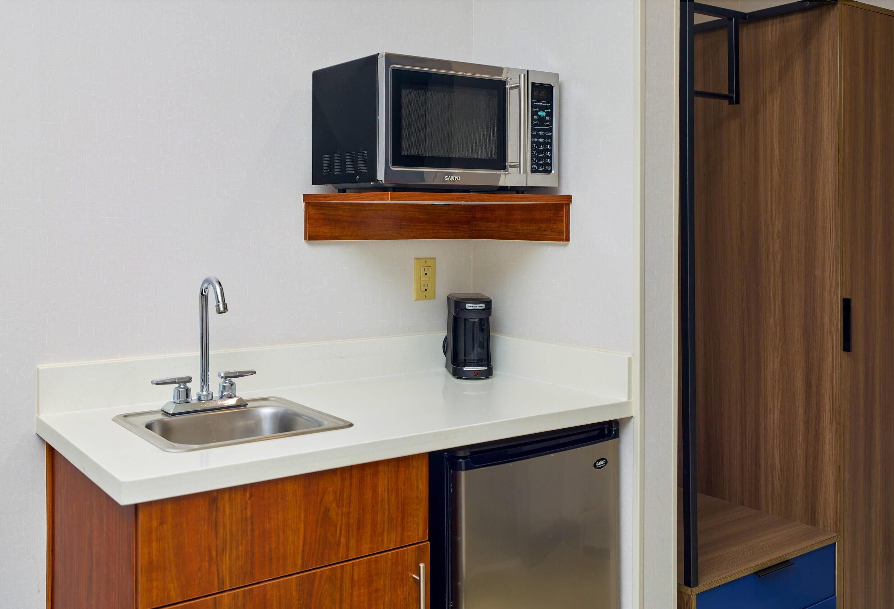 A compact kitchenette with a microwave, coffee maker, and a refrigerator.