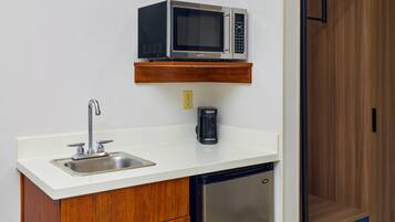 A compact kitchenette with a microwave, coffee maker, and a refrigerator.