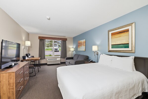 A hotel room with a bed, desk, TV, and a painting on the wall.