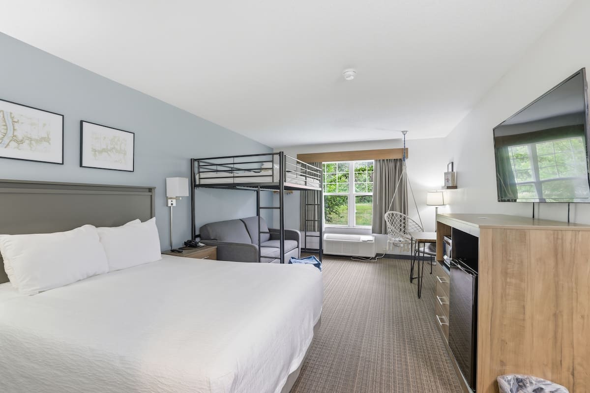 Ein Hotelzimmer mit Etagenbett, Schreibtisch, Stuhl, Fernseher und gerahmten Bildern an der Wand.