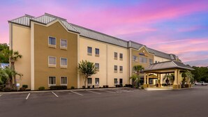 A multi-story hotel with a covered entrance and a parking lot. - Comfort Suites At The University - Conway (Conway)