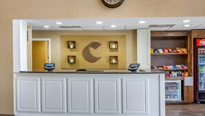 A hotel reception desk with a large clock, a cash register, and a Coca-Cola refrigerator. - Comfort Suites At The University - Conway (Conway)