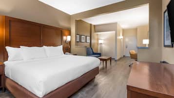 A hotel room with a large bed, a desk, a chair, and a lamp.