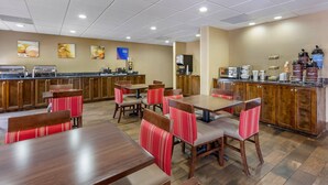A restaurant with wooden tables and chairs, a counter with coffee machines, and a wall with framed pictures. - Comfort Suites At The University - Conway (Conway)