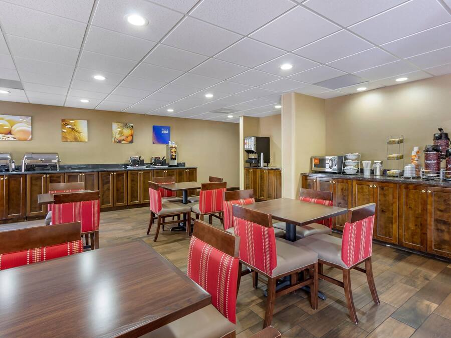A restaurant with wooden tables and chairs, a counter with coffee machines, and a wall with framed pictures.