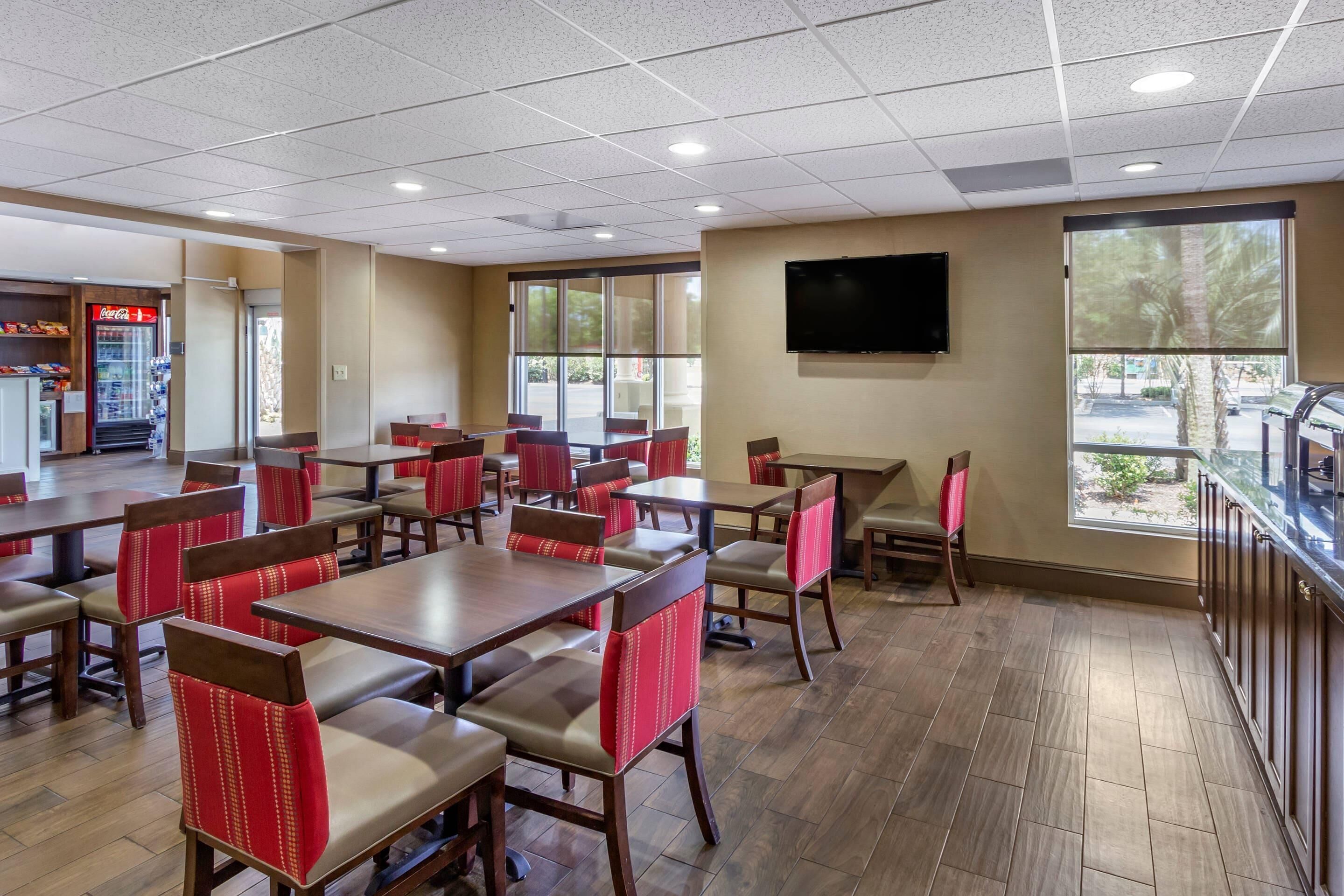 A restaurant with booths and tables, a Coca-Cola refrigerator, and a TV on the wall.