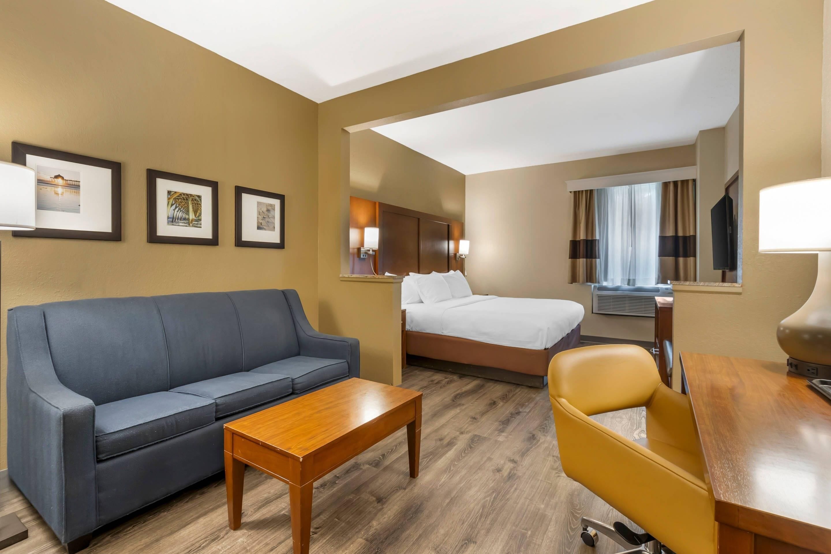 Una habitación de hotel con sofá, cama, escritorio y silla.
