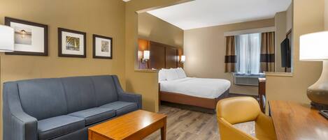 Una habitación de hotel con sofá, cama, escritorio y silla.