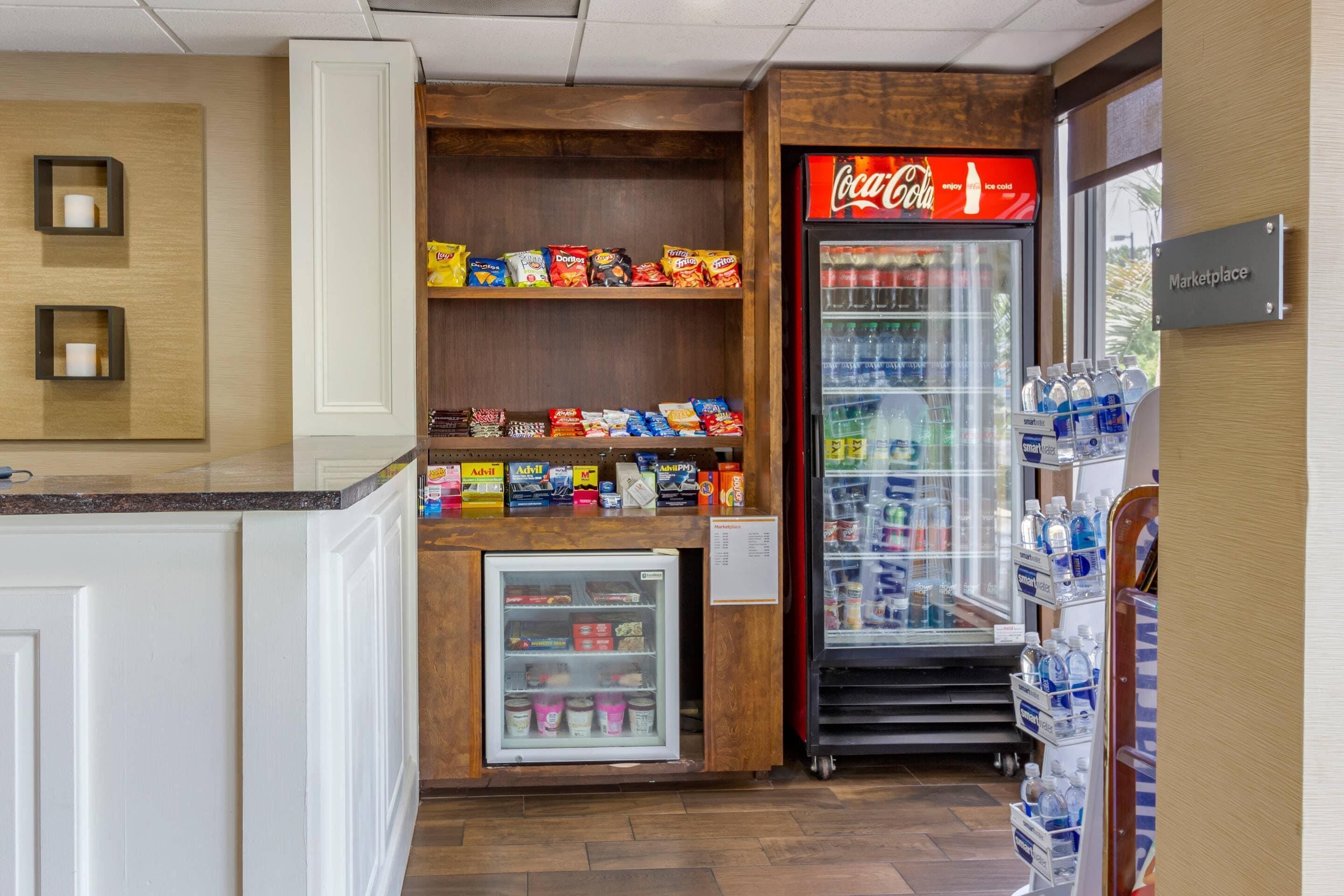 A kitchenette area with a refrigerator, a vending machine, and a Coca-Cola cooler.