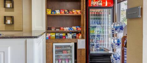 A kitchenette area with a refrigerator, a vending machine, and a Coca-Cola cooler.