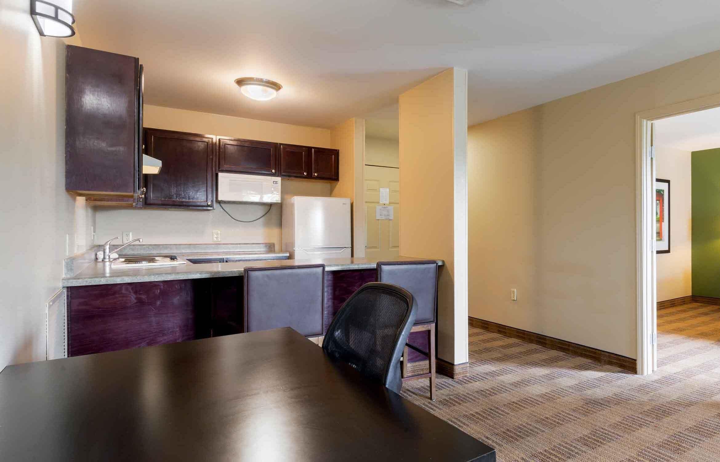A compact kitchen with dark cabinets, a white refrigerator, and a dining area with a table and chairs.