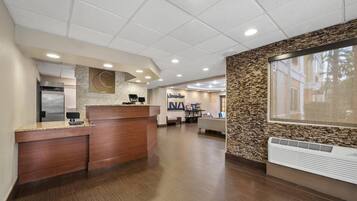 A reception area with a wooden reception desk, a large wall clock, and a reception counter.