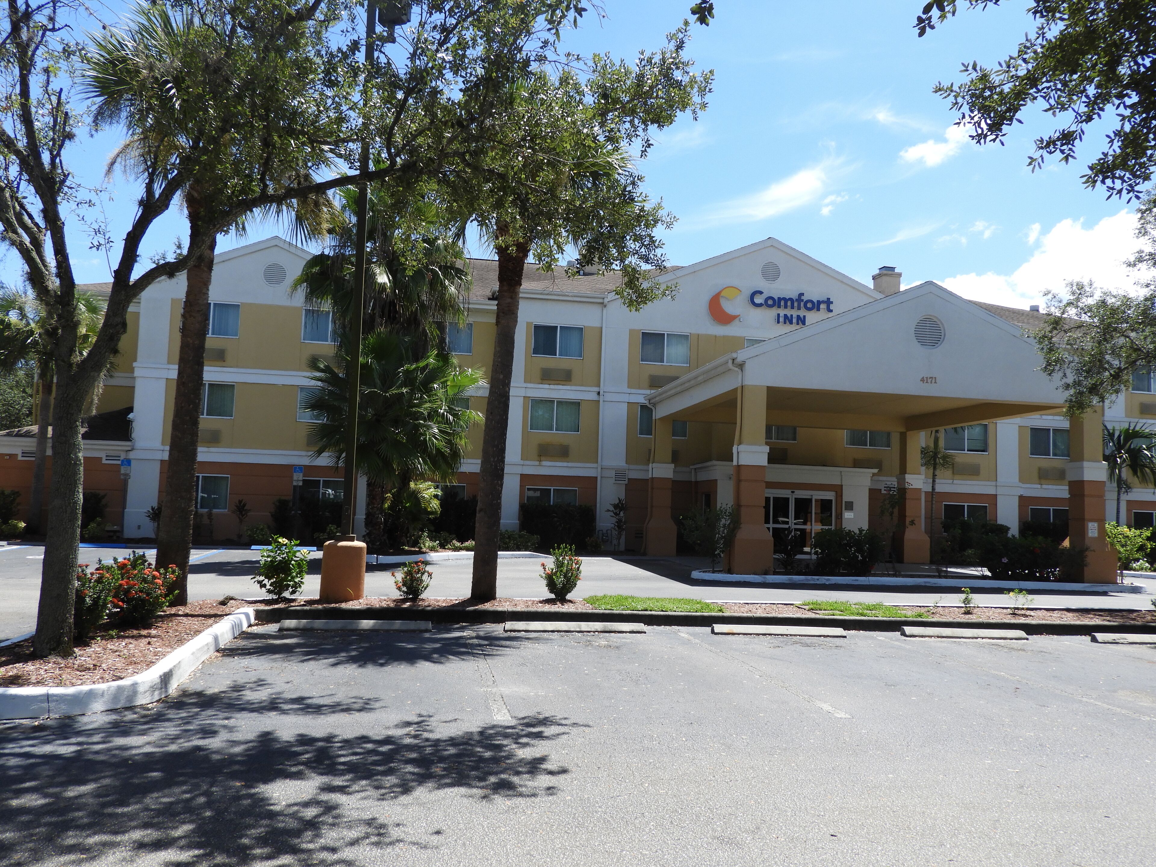 Ein Comfort Inn Hotel mit überdachter Zufahrt, mehreren Etagen und umgebender Bepflanzung.