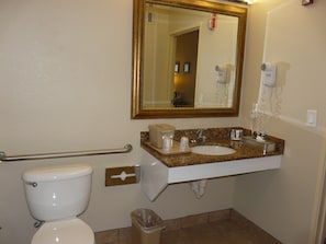 A bathroom with a toilet, sink, mirror, and hand dryer. - Comfort Inn Fort Myers Northeast (Fort Myers)