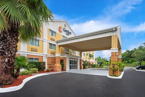 A Comfort Inn hotel with a covered entrance, palm trees, and a clear sky. - Comfort Inn Fort Myers Northeast (Fort Myers)