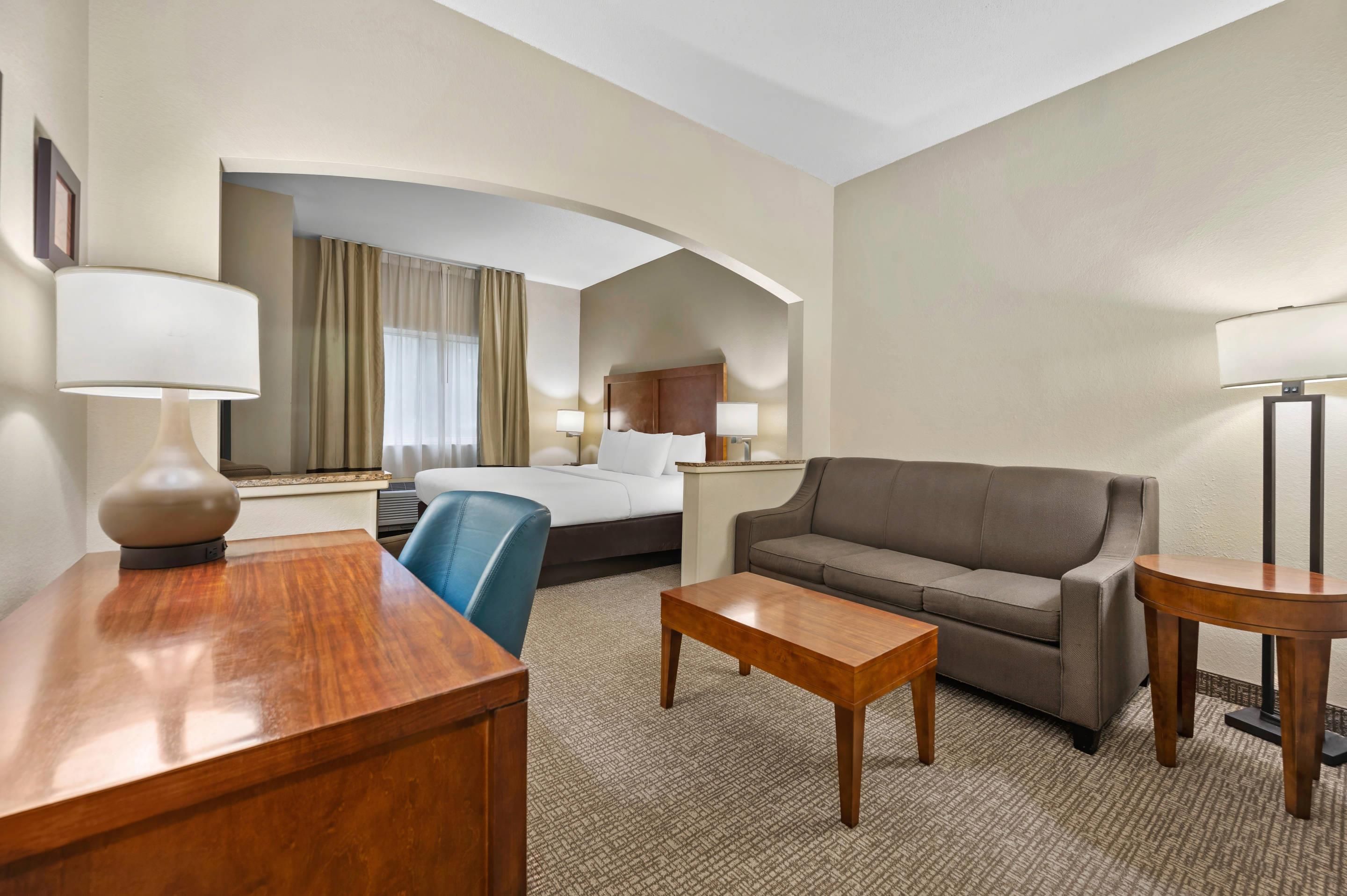 A hotel room with a bed, a sofa, a desk, and a chair.
