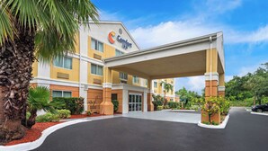 A Comfort Inn hotel with a covered entrance, palm trees, and a clear sky. - Comfort Inn Fort Myers Northeast (Fort Myers)