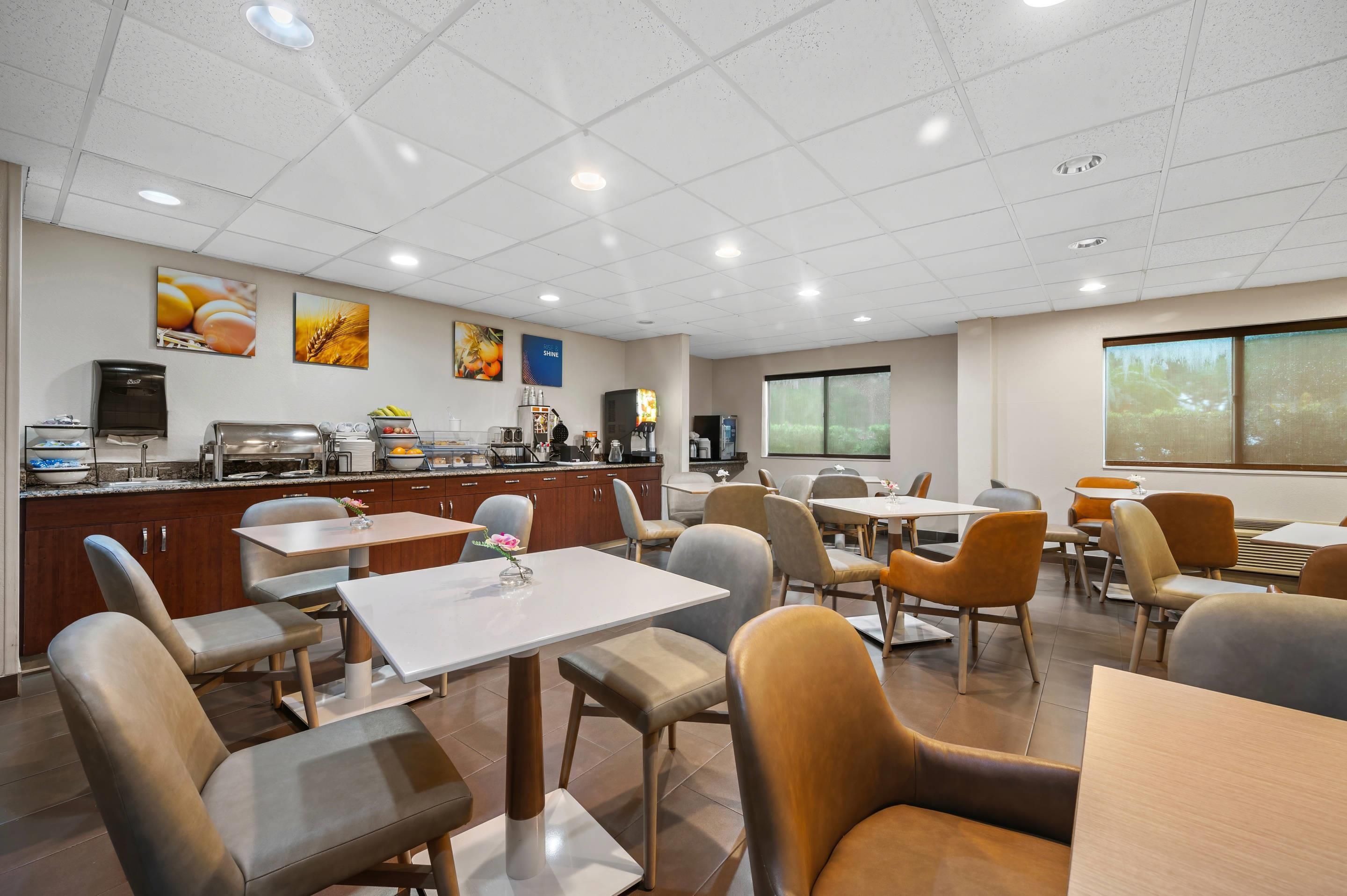 A modern dining area with a buffet, seating arrangements, and a large window providing a view.