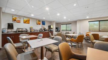 A modern dining area with a buffet, seating arrangements, and a large window providing a view.