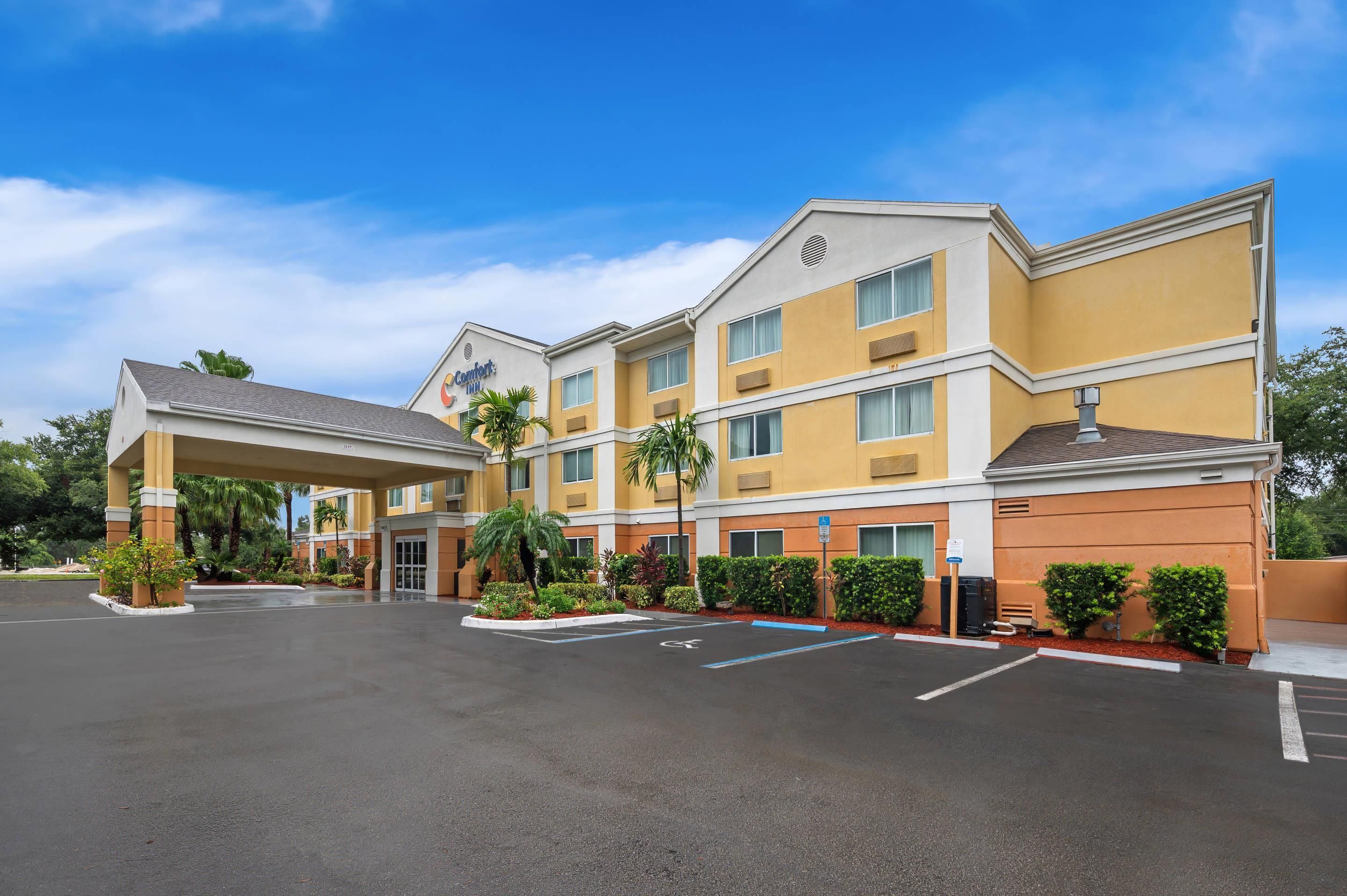 A hotel with a covered entrance, multiple floors, and a parking lot.
