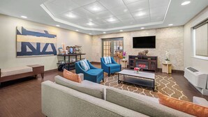 A modern lounge area with a sofa, armchairs, a coffee table, and a fireplace. - Comfort Inn Fort Myers Northeast (Fort Myers)