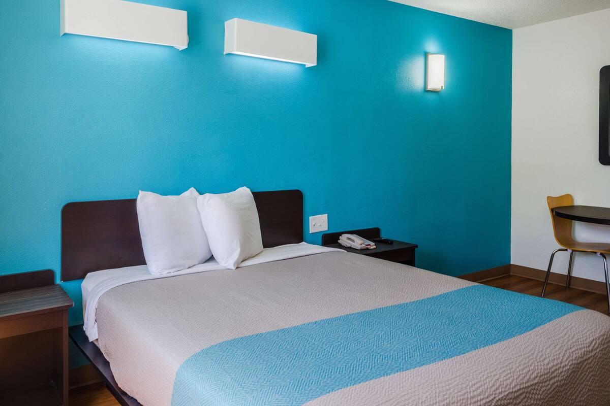 Una habitación de hotel con una cama, un escritorio y una silla.